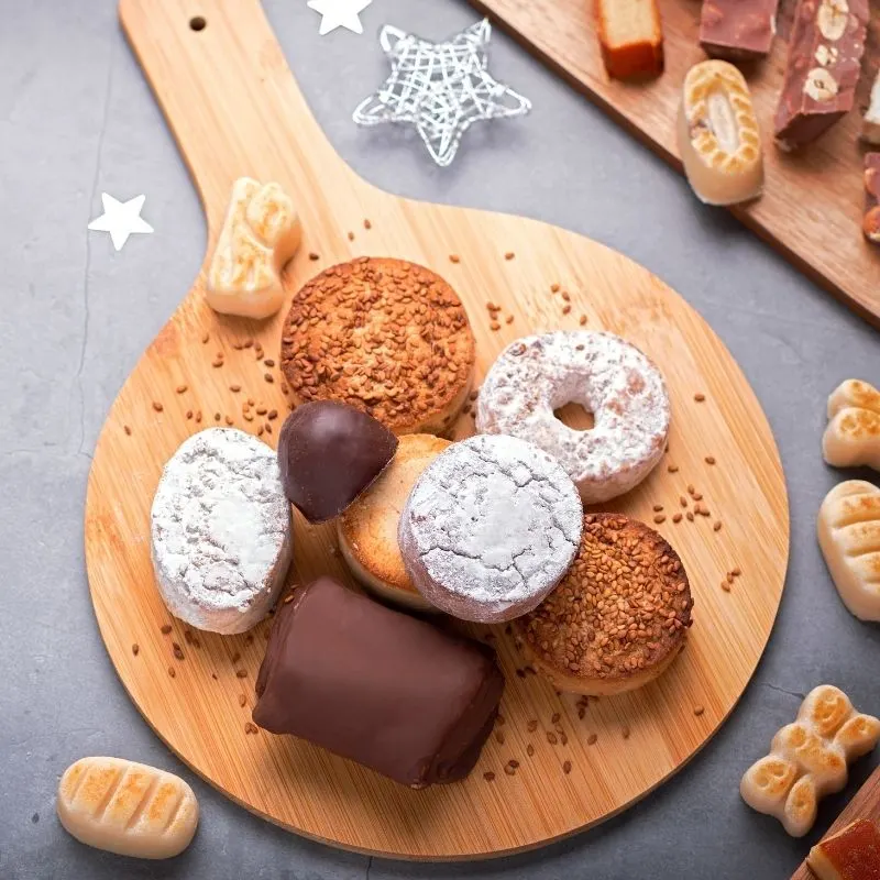 spanish christmas desserts on a wooden table with christmas decorations next to it.