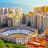 an aerial view of Malaga particularly the bullring surrounded by buildings and the sea