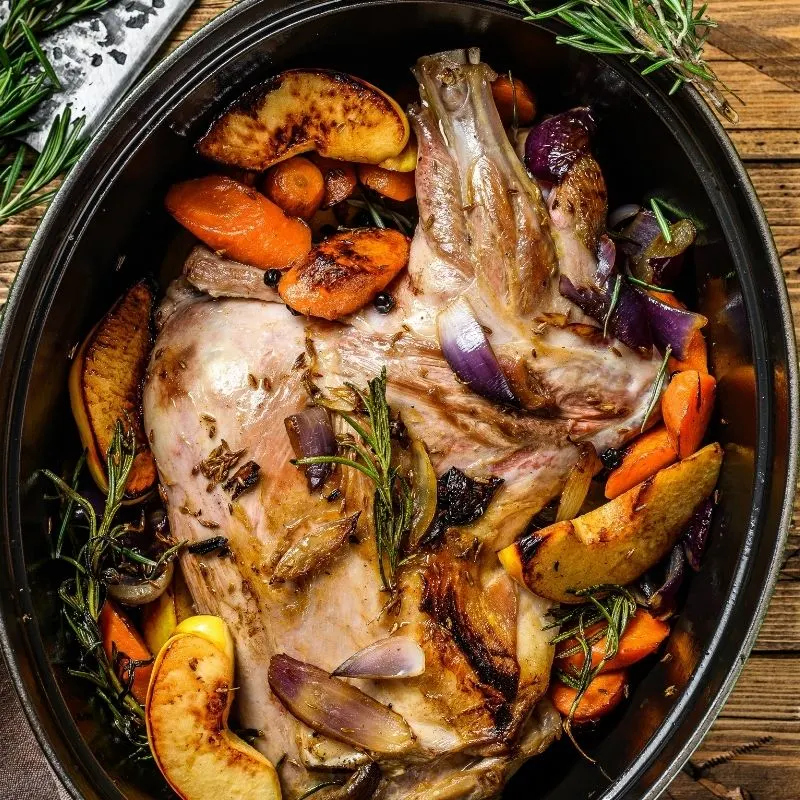 baked lamb inside a pot with vegetables and garnishes