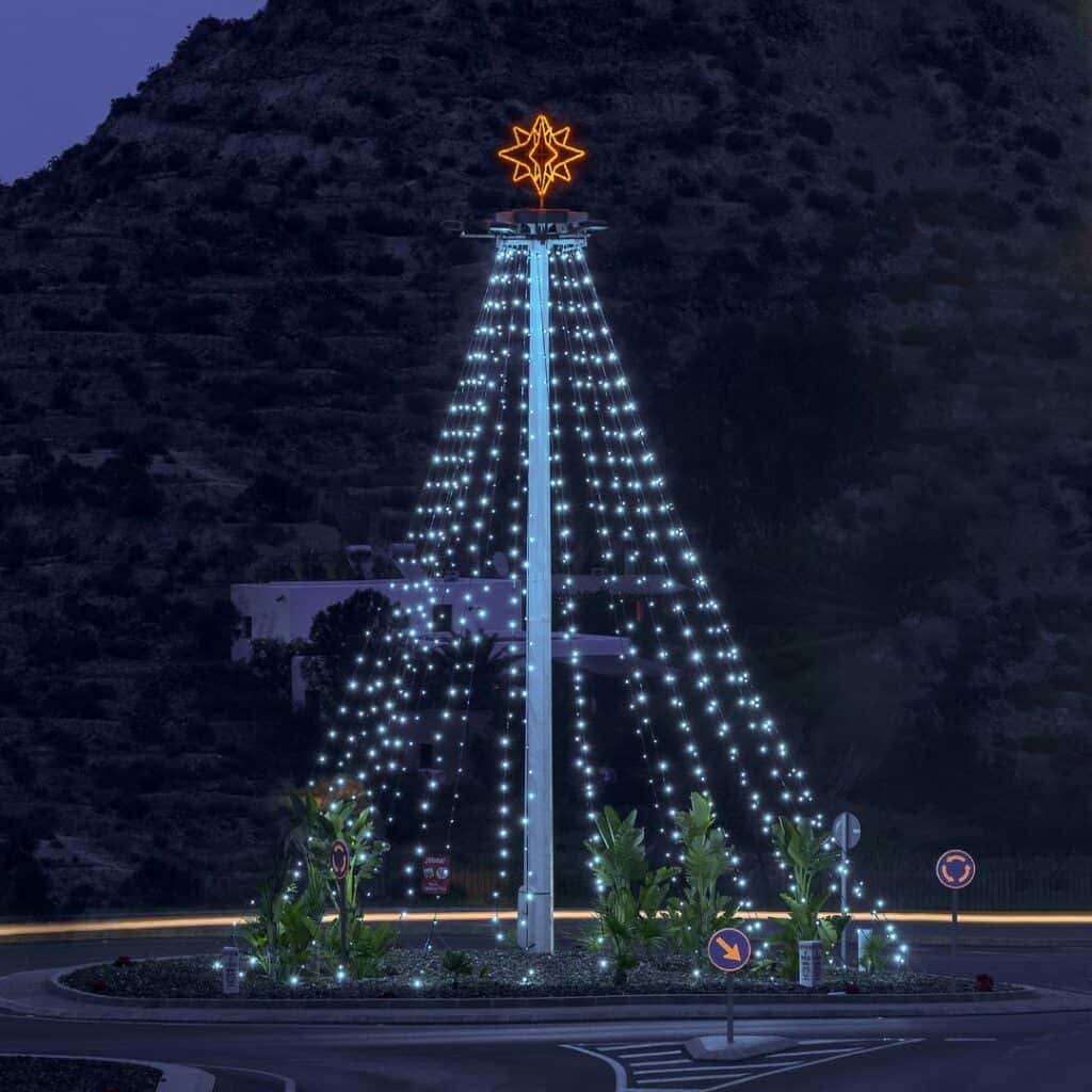 a lighted christmas tree with blue lights and a yellow star in front of a mountain at night