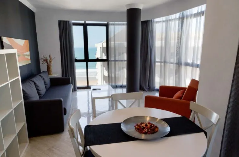 interior of a room in Hotel Spa Cádiz Plaza with a balcony, couch, cabinet, and circular dining table with chairs