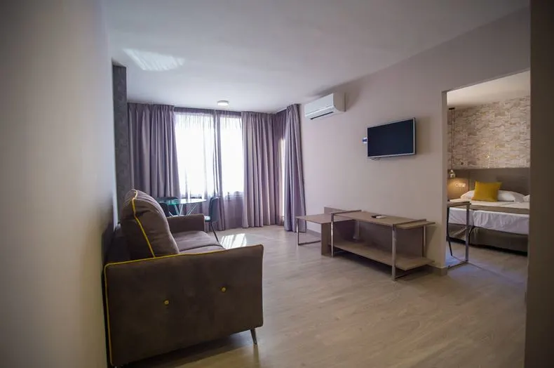 interior of Marbella Inn with cream walls, couch, television, a window, and a look at the bedroom