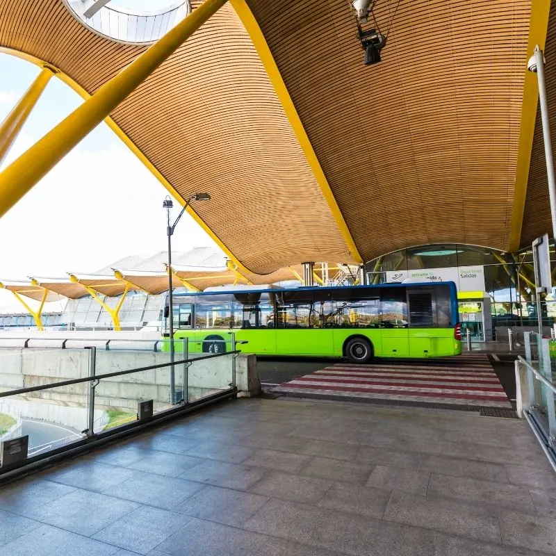 A green bus departing from a bus station to travel