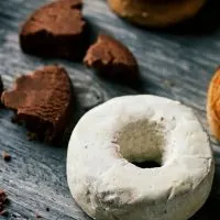 close up of a donut shaped white wine cookies with black crumbs on a gray table