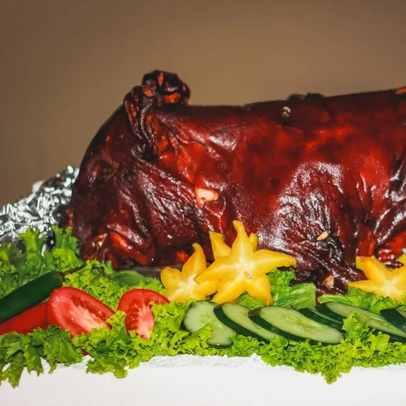 closeup of a roasted pig with vegetables around it