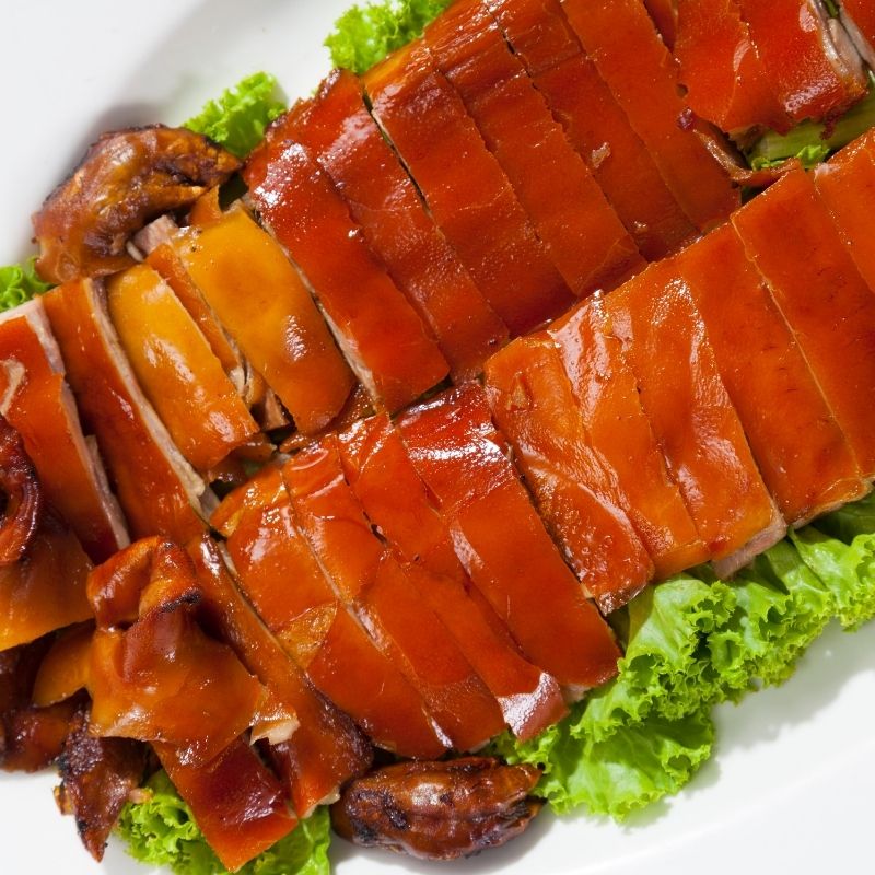 closeup of a chopped suckling pig recipe on a vegetable and plate