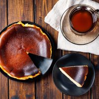 Spanish Cheesecake on a wooden table next to a cup of tea