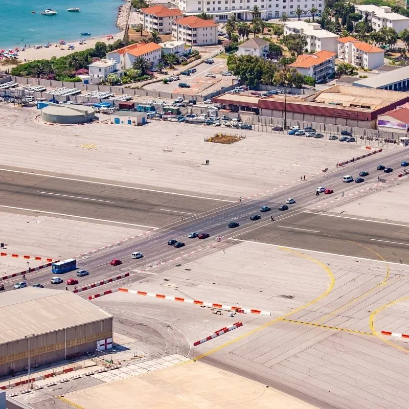 From Malaga Airport to Gibraltar, a view of a busy airport from a top floor with roads, cars, and buildings