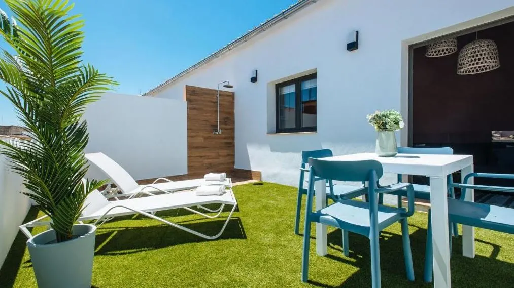 outside Lola de Triana Apartment with a beach bed, and high table and chairs on the grass