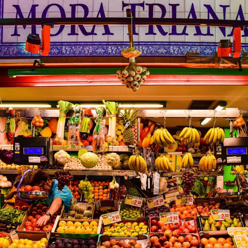 a stall in Triana Market filled with fruits displayed like bananas, oranges, etc.