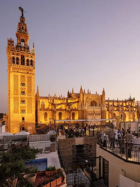 a view of a tower and a building during the night with a lot of people visiting