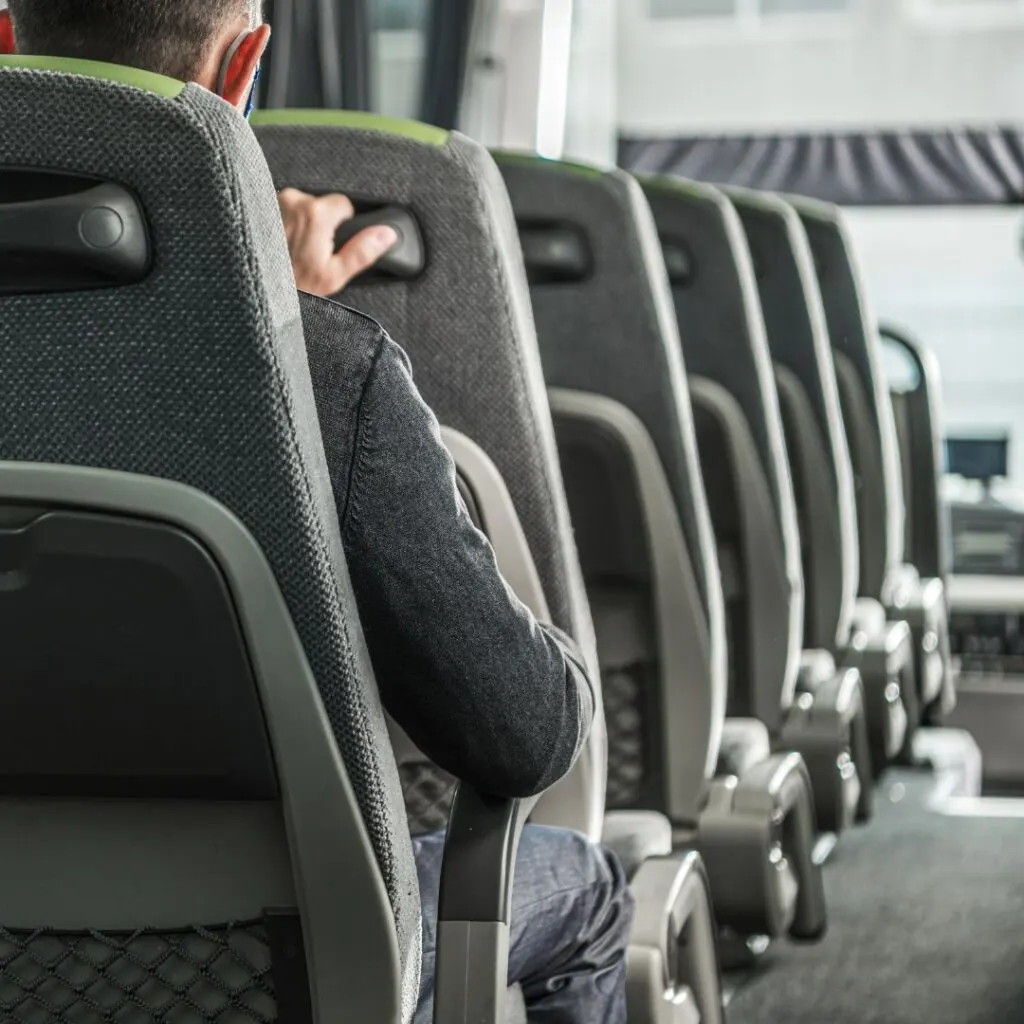 a person in a gray seat is sitting in the back of a bus