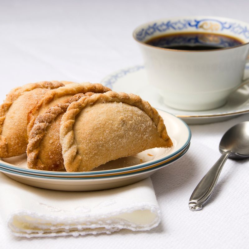 Spanish sugar cookies on a plate, next to a cup of coffee