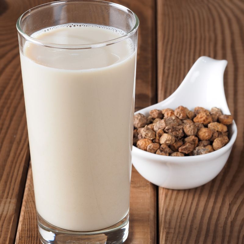 horchata in a tall glass with tiger nuts next to it on a wooden table. 30 Most Famous Spanish Drinks