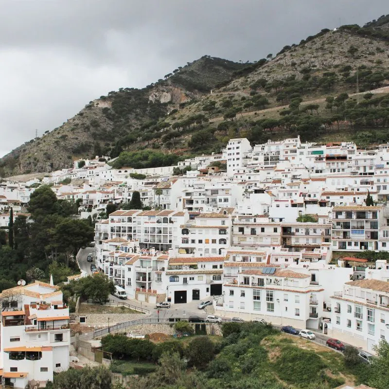 white houses on a base of a mountain and the mountain peak on the background