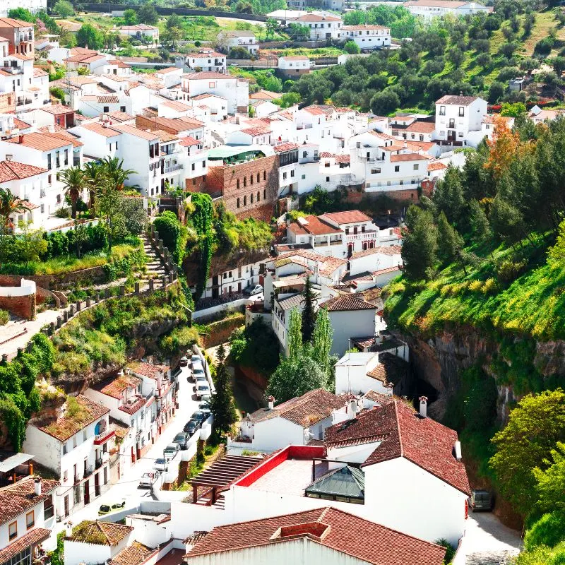 aerial view of Setenil de las Bodegas with many white houses with red roof and green trees around