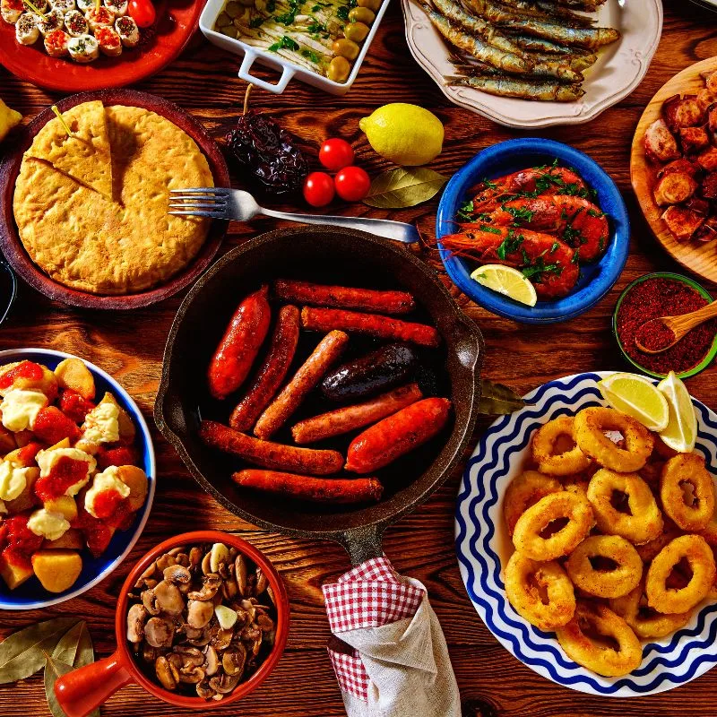 various spanish tapas plates on a wooden table that you can enjoy on a tapas tour when visiting Seville in June