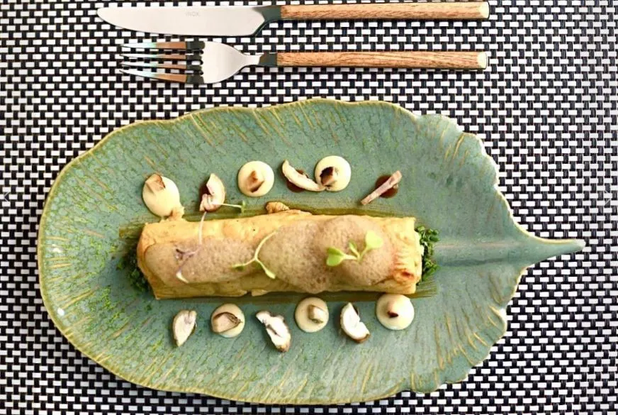 Bartolomea, a closeup of a spanish food on a banana glass plate with a knife and fork at the side