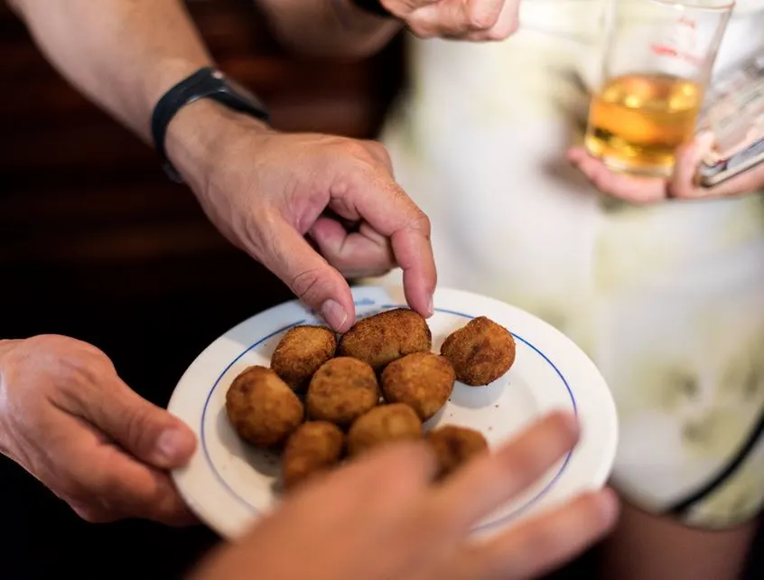 El Rinconcillo, a closeup of a person holding a plate with balls and another person picking it