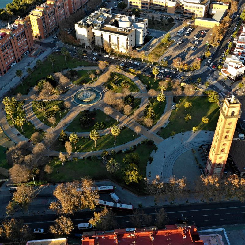Jardines Torre de Los Perdigones, an aeiral view of a circular park filled with trees and a tower on the other edge