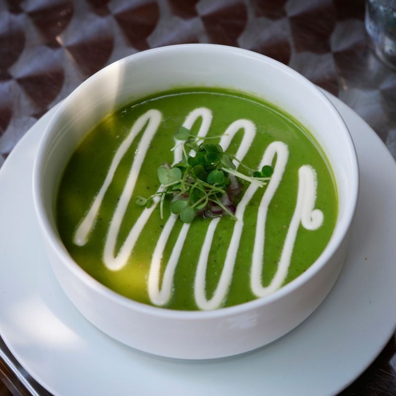 cold asparagus  soup served in a white bowl decorated with cream
