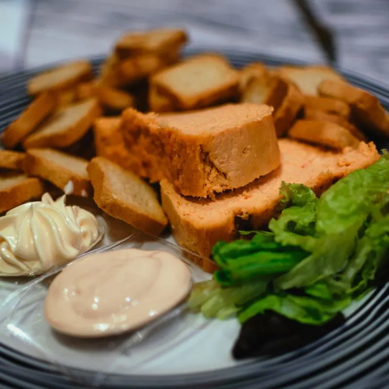 pastel de cabracho, a plate with tapas or bread with vegetable on the side and sauce