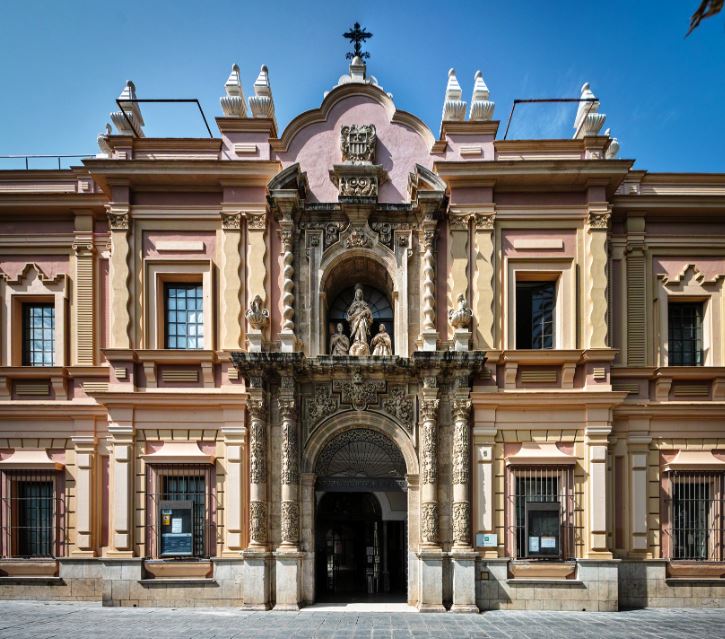 a facade of a buidling that was once a convent, at the center of the second floor there is a statue of Mary and two people  praying