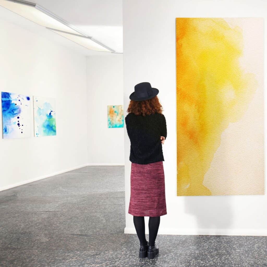 a woman looking at a painting in an art gallery