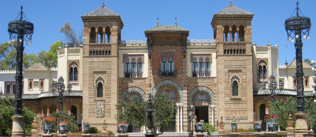 Facade of Museum of Art and Traditional Culture with intricate details and two columns, lamps, and flowers