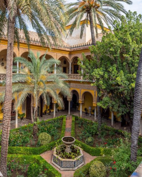 interior of Palacio de las Dueñas with columns, trees, and plants