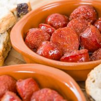chucks of spansih chorizo recipe with cider served in a clay pot.