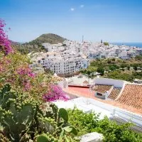 a view of the white houses in frigiliana with flowers and plants on the forefront