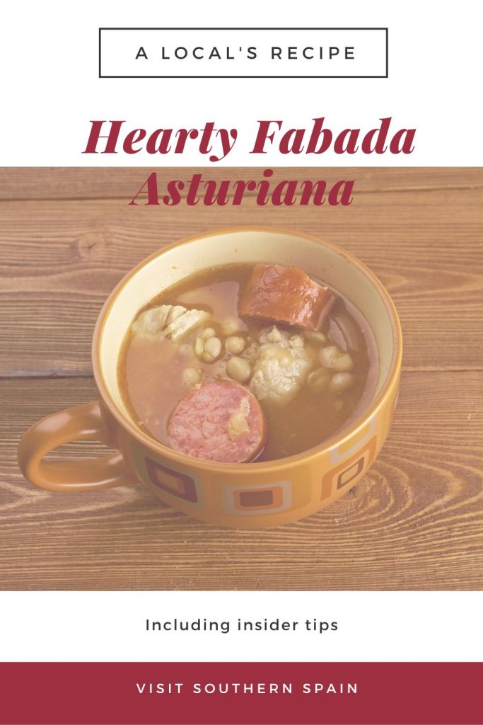 A photo with fabada asturiana in a clay bowl on a wooden table. On top of the photo it's written hearty Fabada Asturiana. 