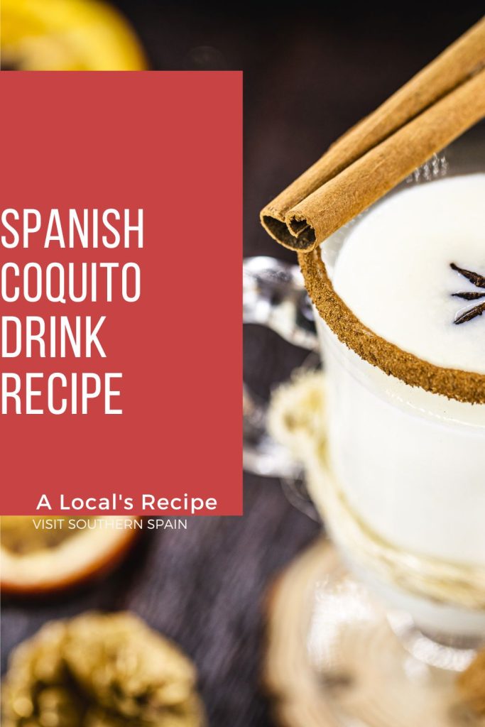 A closeup with a glass of coquito decorated with cinnamon. On the left of the photo it's written Spanish coquito drink recipe on red background.