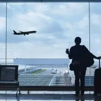 Woman holding here luggage in an airport while looking at an airplane taking off, best hotels near Malaga Airport