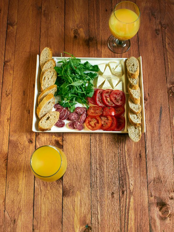 a plate with Mediterranean breakfast on a wooden table and 2 glasses of orange juice.