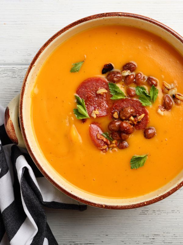 creamy Orange Lentil Soup in a bowl with chorizo toppings