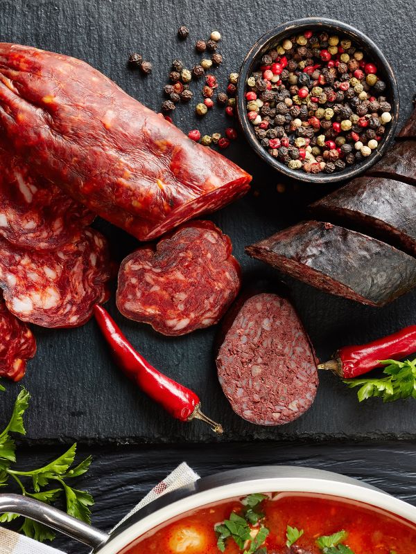 fabada ingredients such as chorizo, black pudding and spices on a black surface.