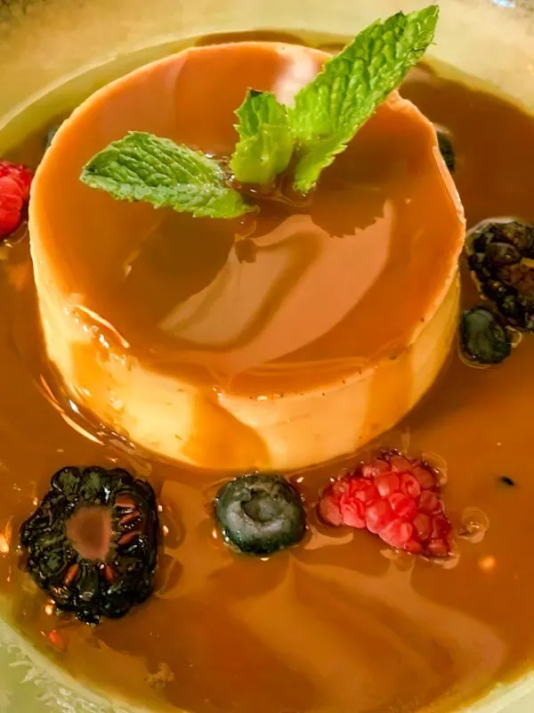 flan cake with pumpkin decorated with dulce de leche sauce, forest fruits and a mint leaf