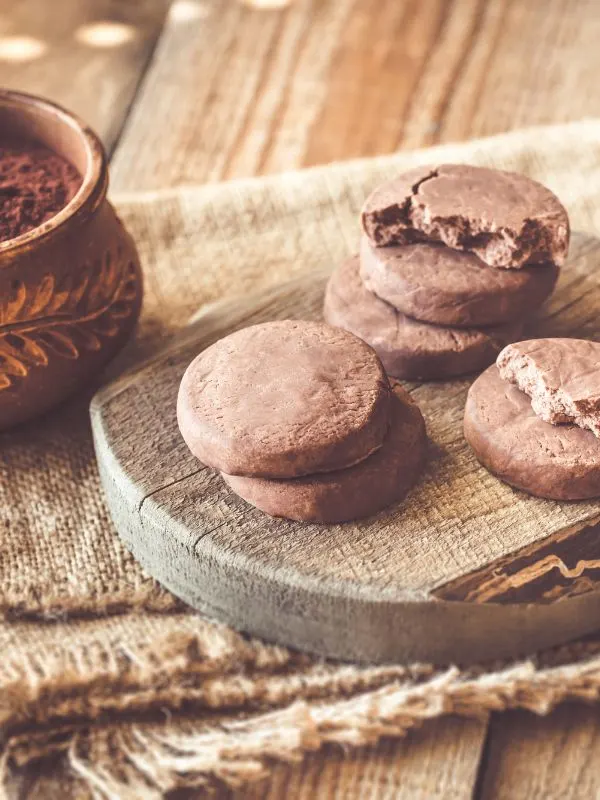 traditional Christmas cookies with cocoa on a wooden table next to a bowl of cocoa powder