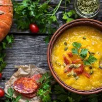 pumpkin chorizo soup in a clay bowl on a wooden table