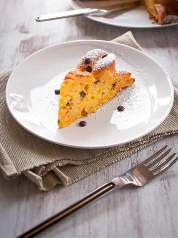 pumpkin spice cake with chocolate chips on a white plate and next to the plate there's a fork.