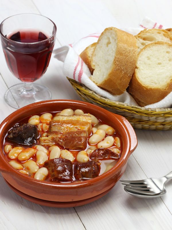 serving fabada asturiana with fresh bread and a glass of red wine