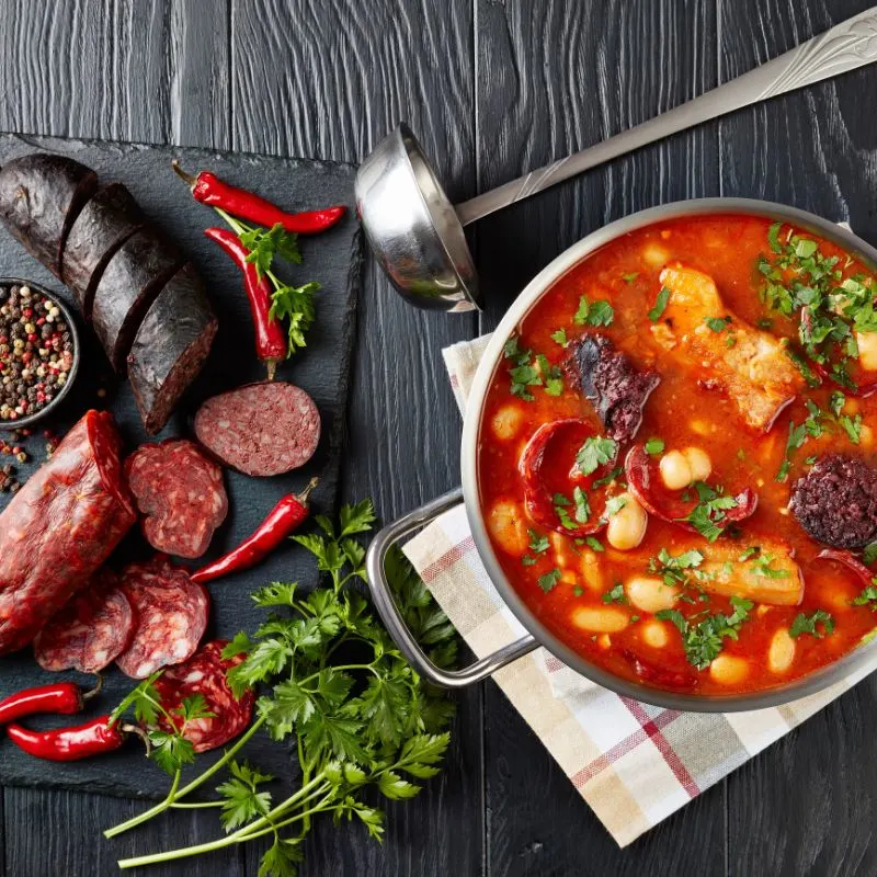 cocido madrileno
in a pot and next to it there are ingredients for the bean stew on a black surface.