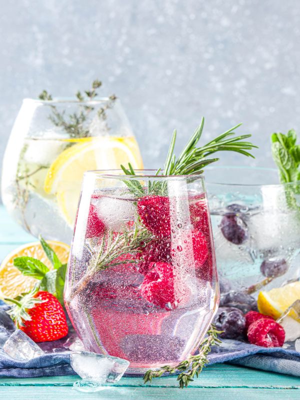 3 glasses of spanish gin and tonic with various fresh fruits.