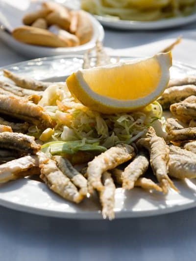 Plate of deep-fried anchovies with lemon and salad. 25 Ideas for the Best Spanish Themed Party 
