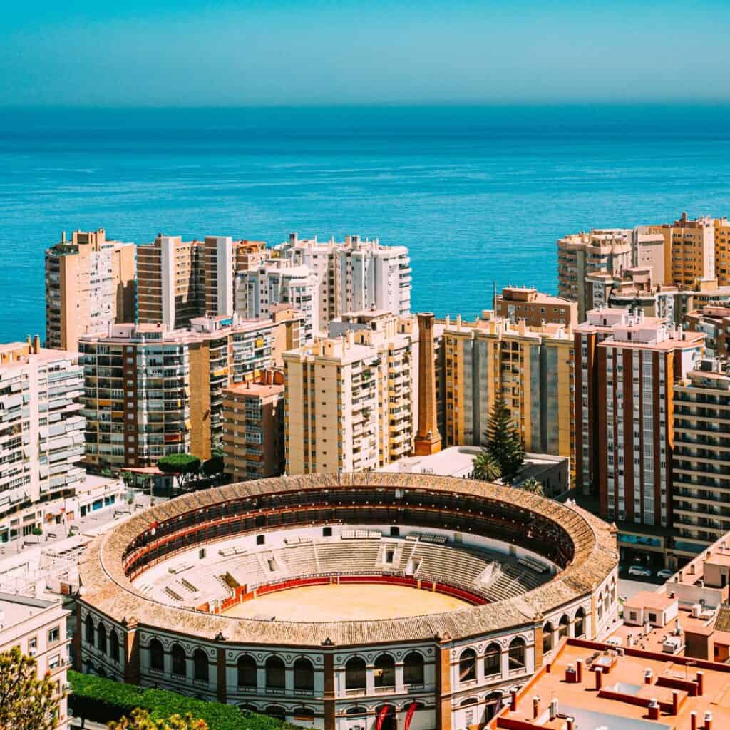 a bullring in malaga, spain surrounded with buildings and a view of the sea
