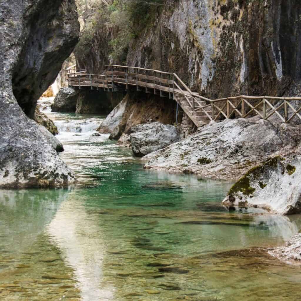 a bridge over a river in the middle of a canyon