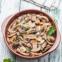 spanish garlic mushrooms in a pot with fresh parsley