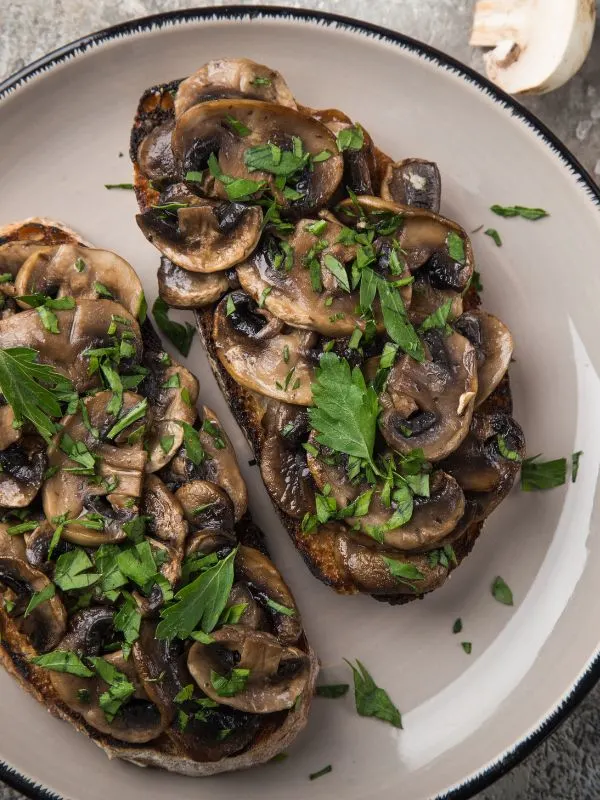 Spanish garlic mushrooms on toast, on a white plate.